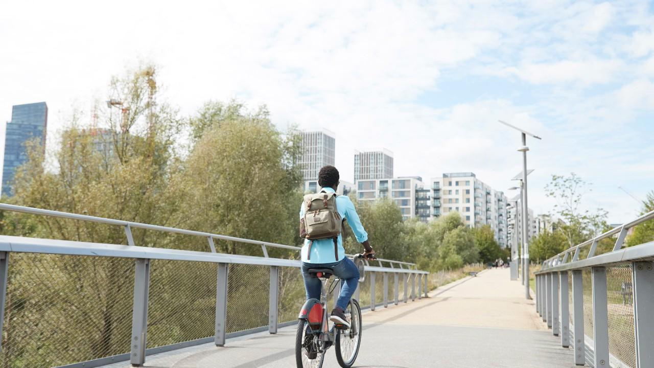 骑自行车从桥上到城市的女孩.